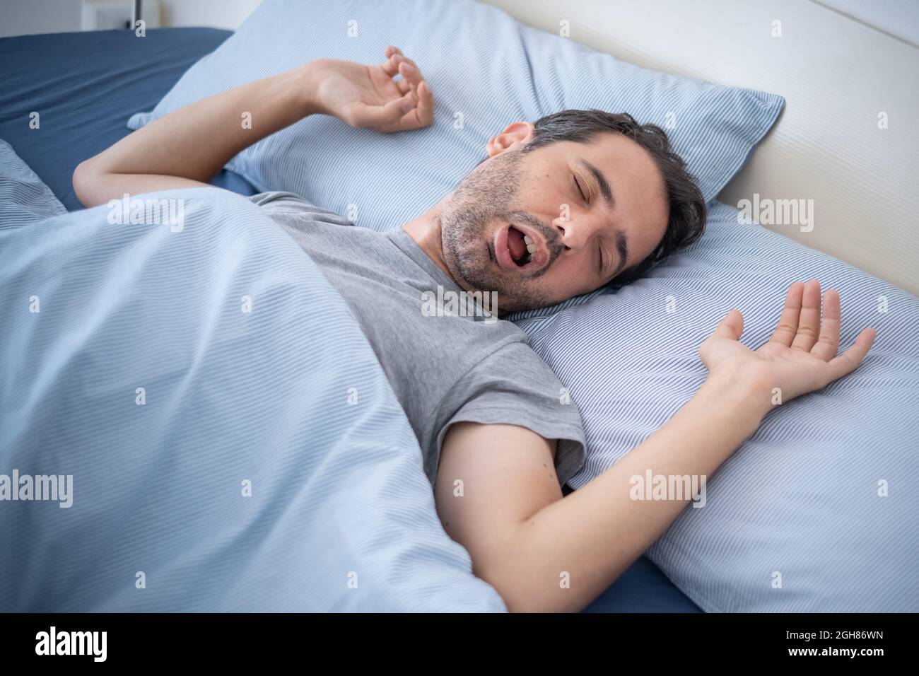 Man snoring loudly in his bed while sleeping Stock Photo Alamy