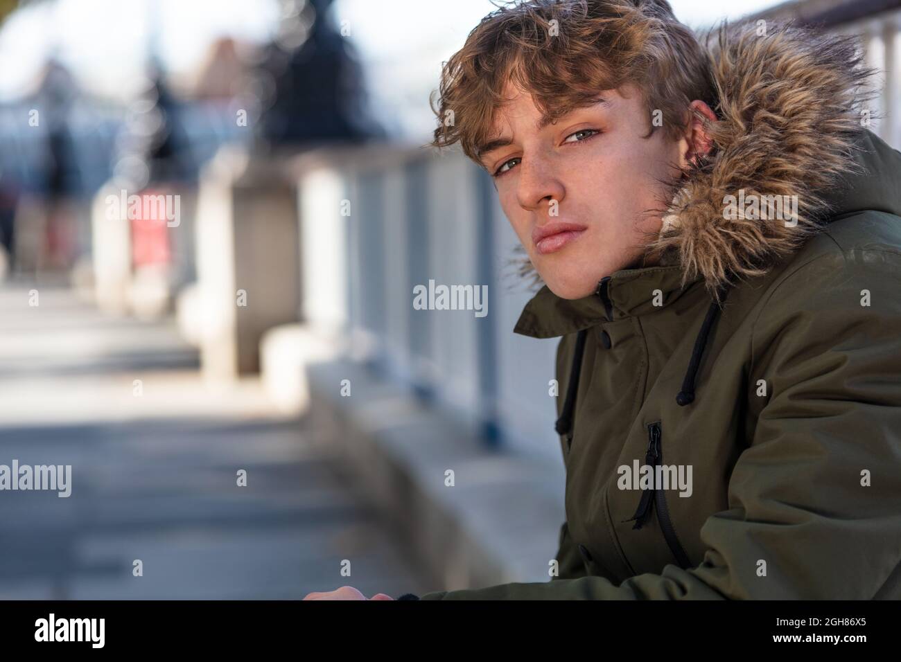 Male young adult teenager boy wearing a parka jacket outside in an urban city Stock Photo