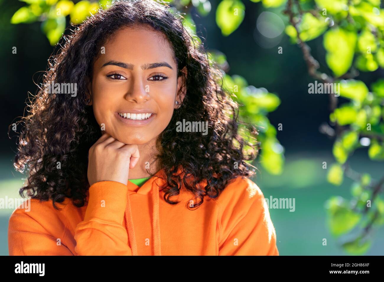 Outdoor portrait of beautiful happy mixed race African American girl teenager female young woman thinking and smiling with perfect teeth with a natura Stock Photo