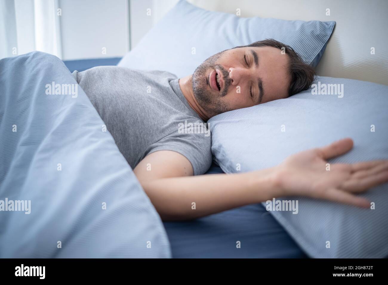 Man snoring loudly in his bed while sleeping Stock Photo Alamy