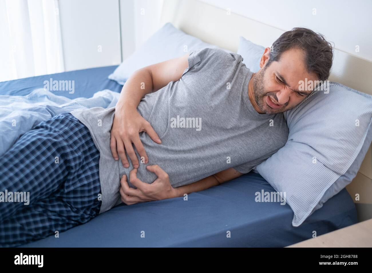 man-in-bed-suffering-from-heartburn-and-stomach-pain-stock-photo-alamy