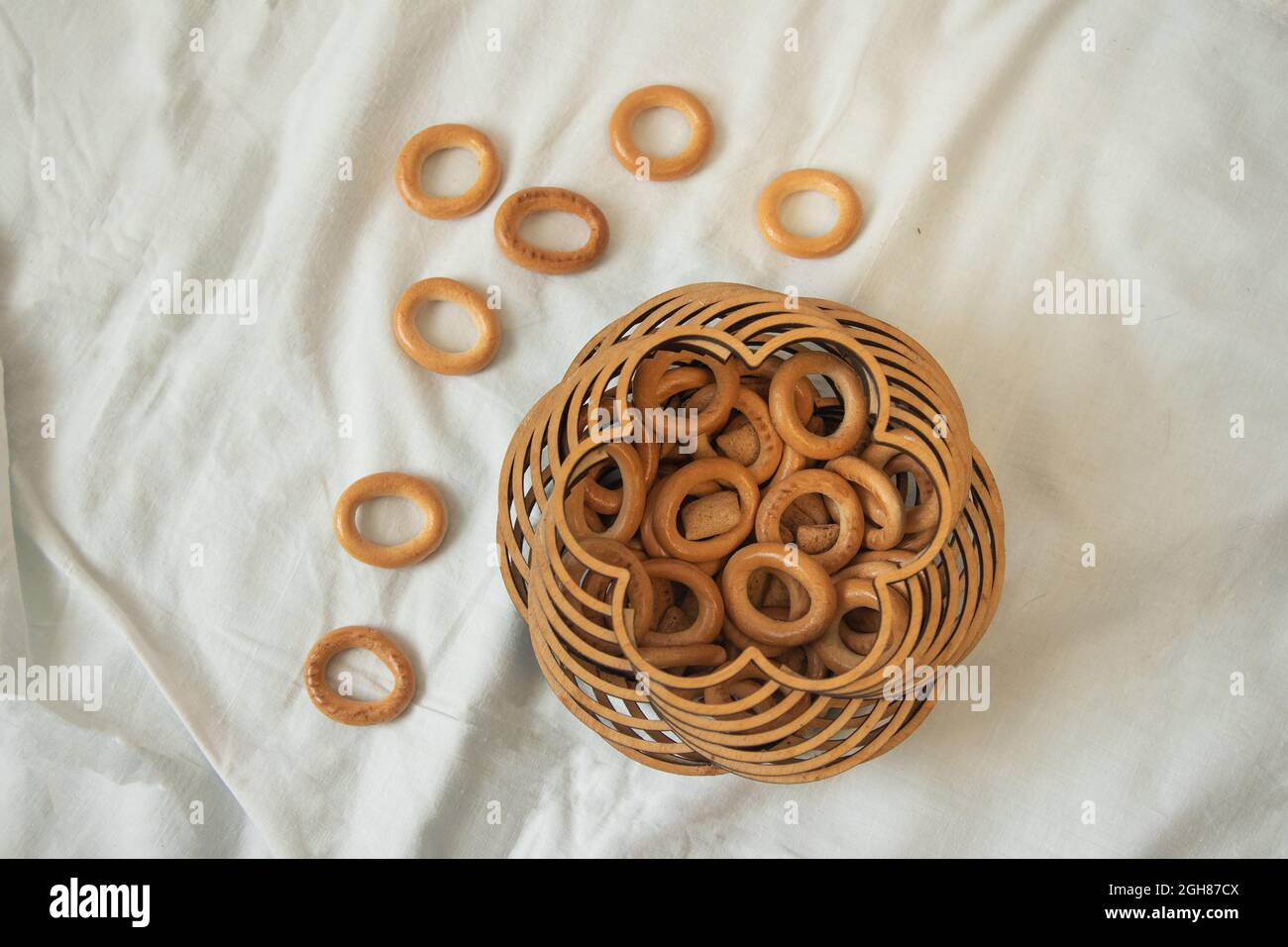 Drying bagels in authentic carved wooden box on white tablecloth, lifestyle photo in neutral colours. High quality photo Stock Photo