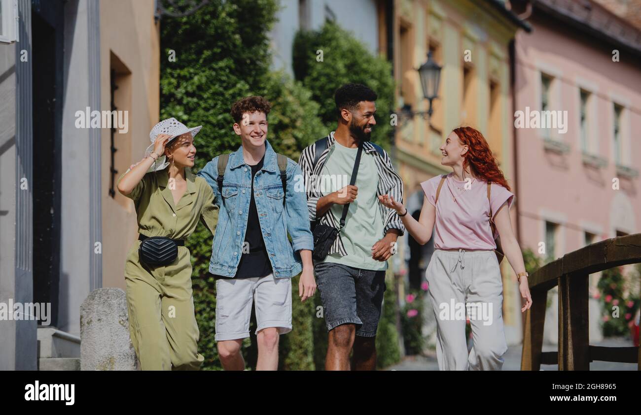 Front view of group of happy young people outdoors on trip in town, walking and talking. Stock Photo