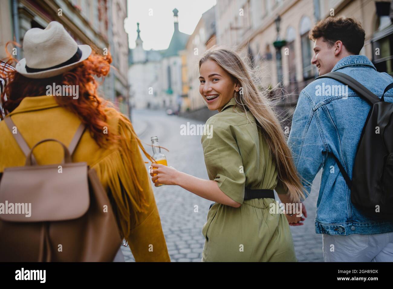 Rear view of group of happy young people outdoors on trip in town ...