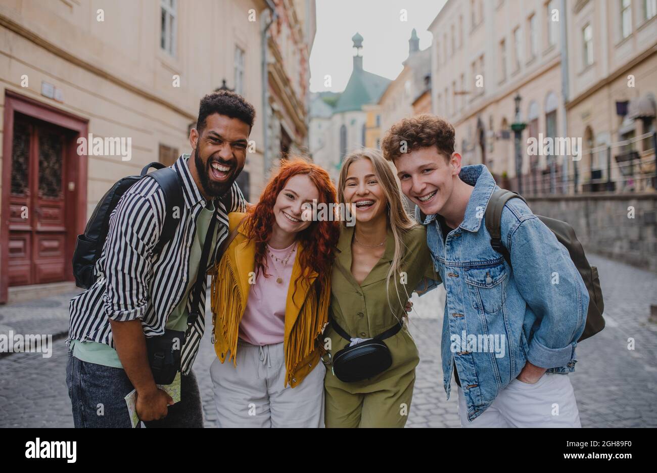 Front view of group of happy young people outdoors on trip in town, looking at camera. Stock Photo