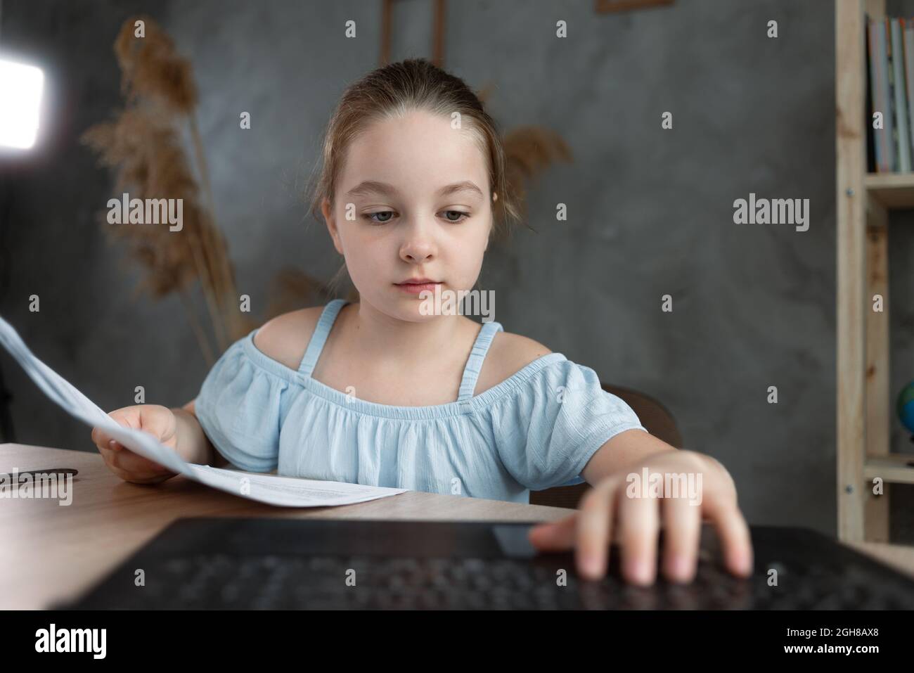 Smart preschool schoolgirl doing homework with laptop at home. web camera view. The child uses gadgets to study. Education and training for children. Stock Photo