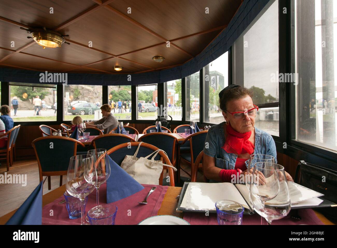 TURKU, FINLAND ON JUNE 29, 2013. Unidentified woman ready to order lunch. Furnishings and people in the background. Editorial Stock Photo