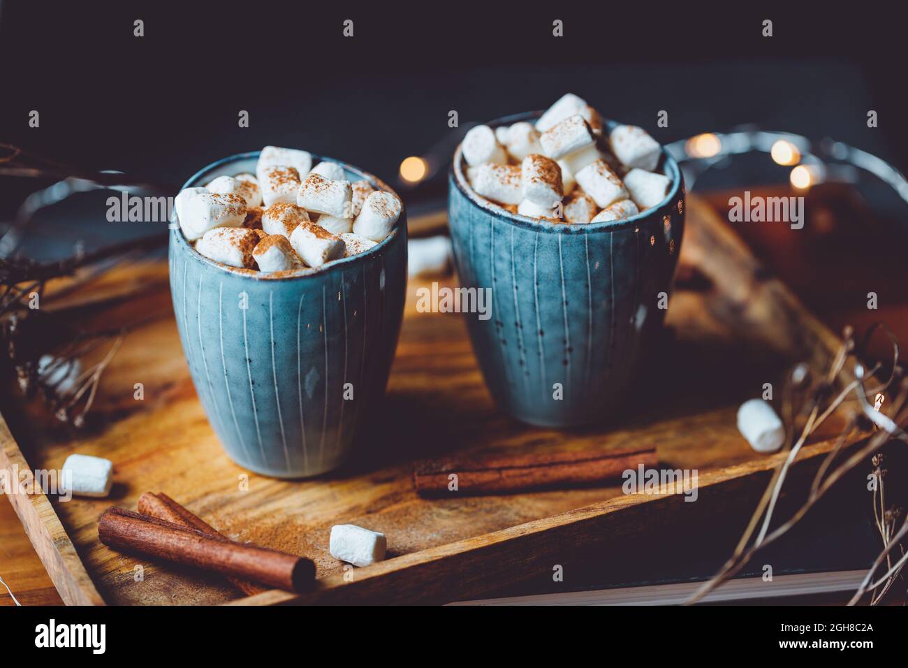 Hot chocolate with marshmallow and cinnamon in blue ceramic cups on a table. The concept of cosy holidays and New Year. Stock Photo