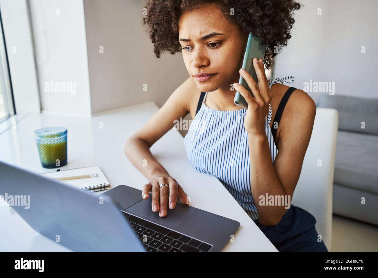Focused curly-haired woman making a phone call Stock Photo