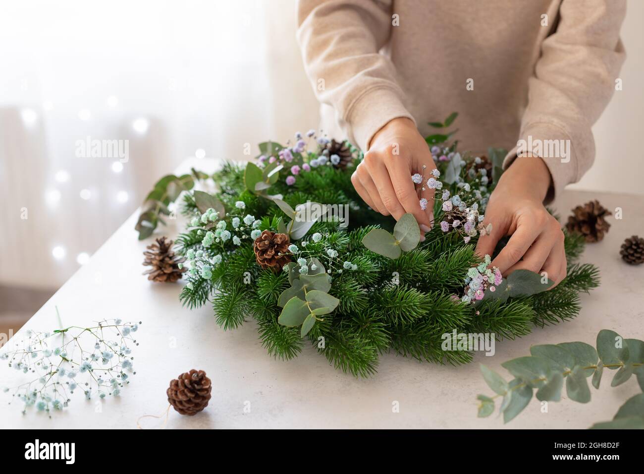 female hands making Christmas wreath with flowers Stock Photo