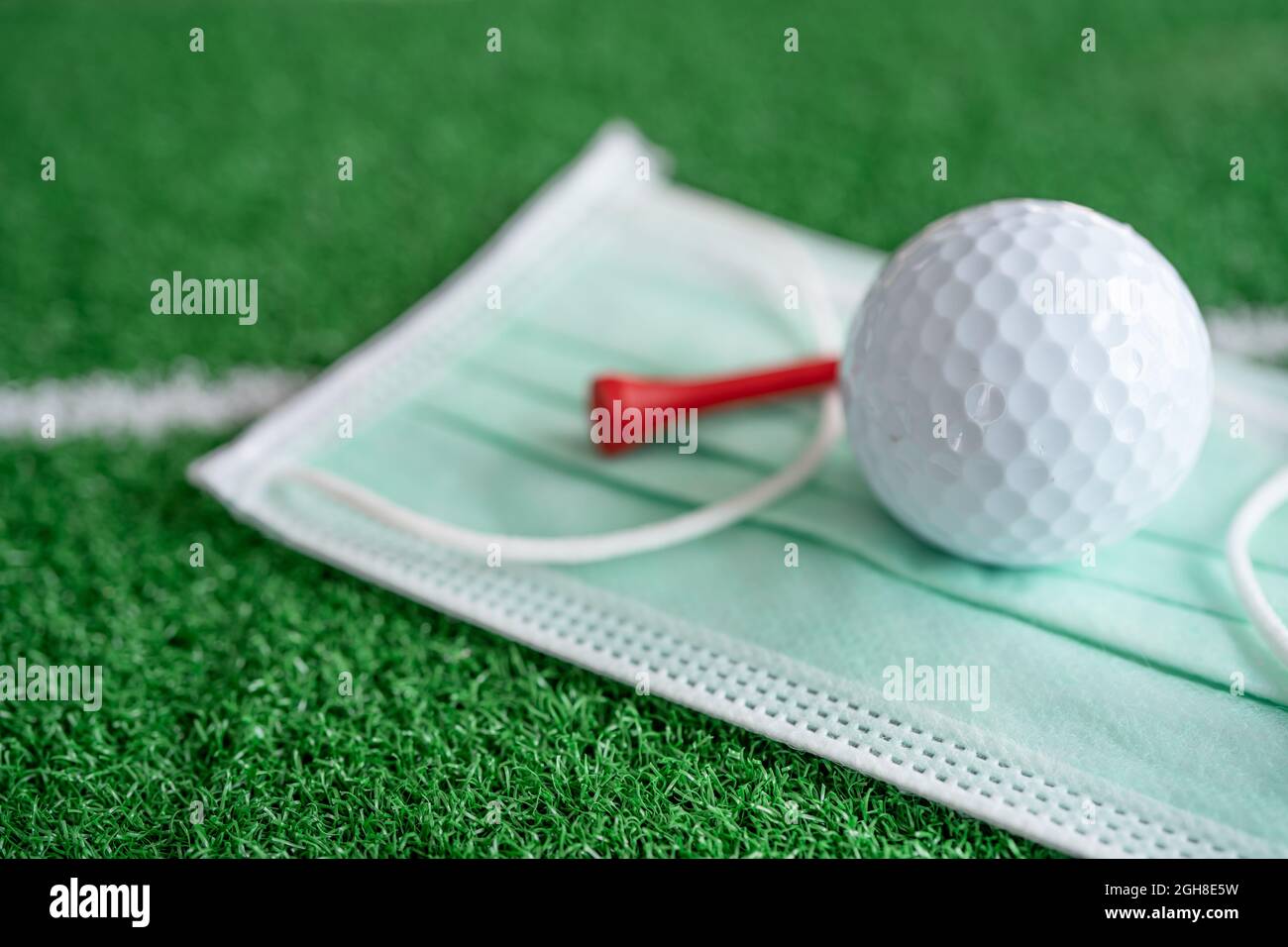 Golf ball with tee on face mask for protect covid-19 coronavirus in tournament at golf course. Stock Photo