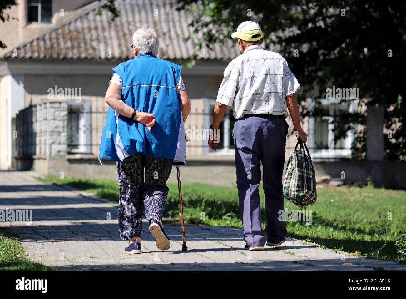 Elderly couple walking on a town street. Old man and woman with cane, life in retirement Stock Photo