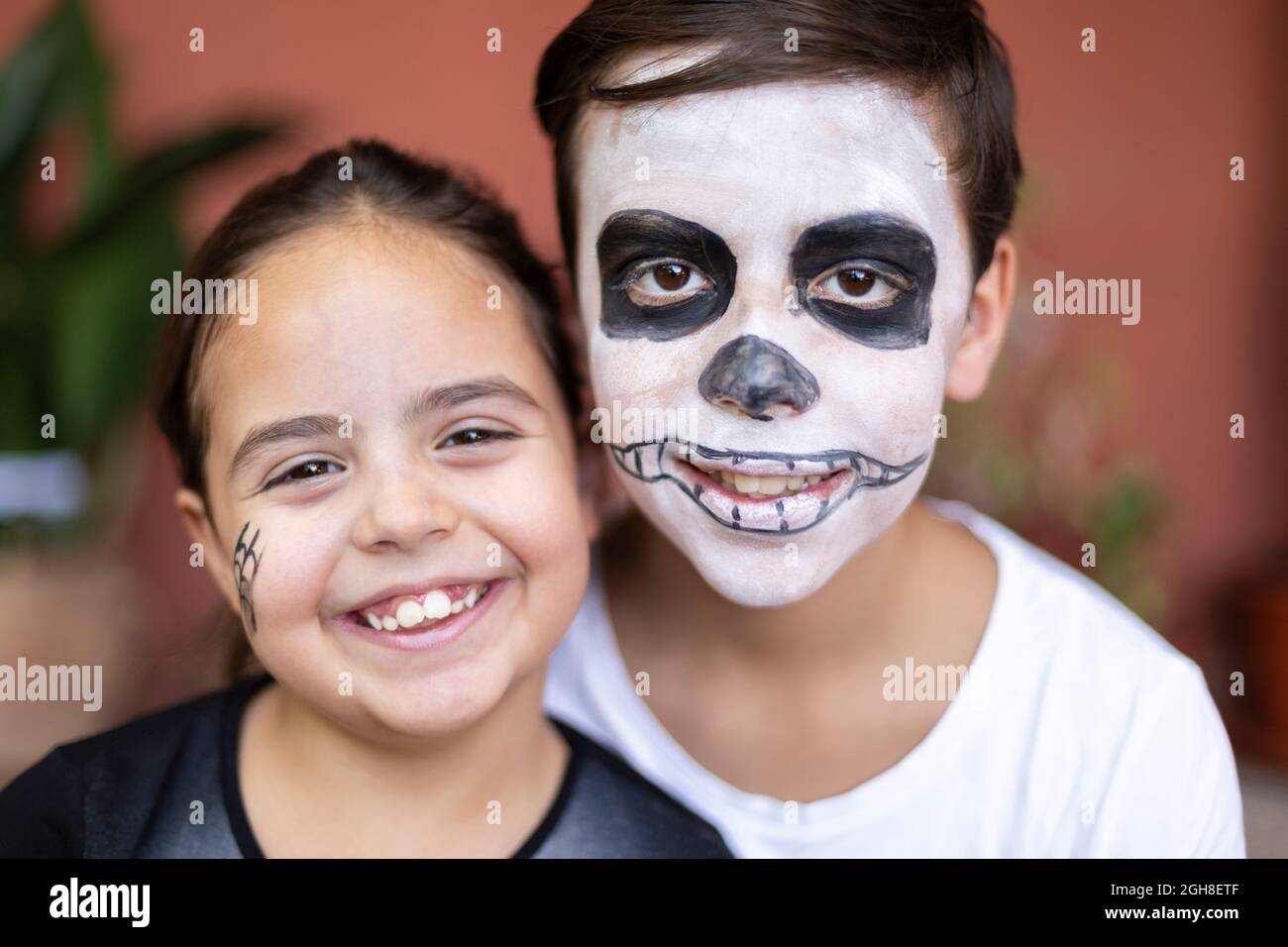 Close up of caucasian boy and small child with make up for Halloween party. They are smiling. Stock Photo