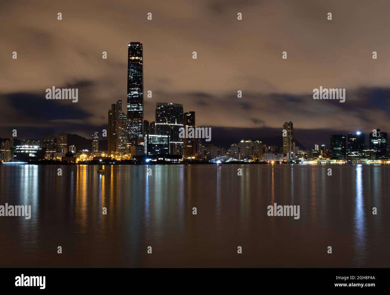 Taken from Hong Kong Island across Victoria Harbour to Kowloon and the ICC skyscraper.  Beautiful reflections in a silky sea from a long exposure. Stock Photo