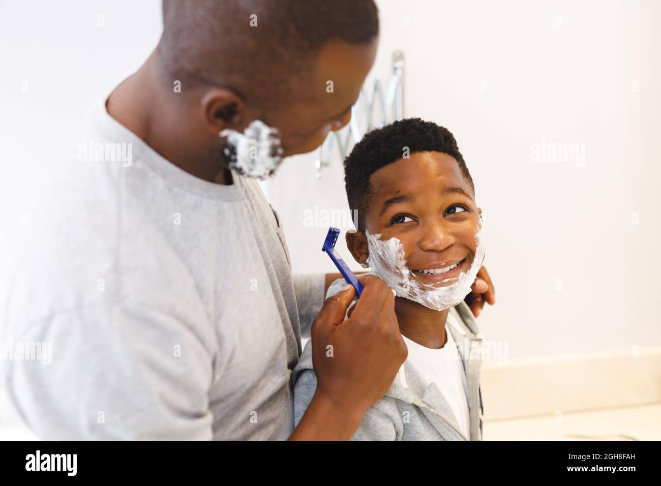 African american father with son having fun pretending to shave in bathroom Stock Photo