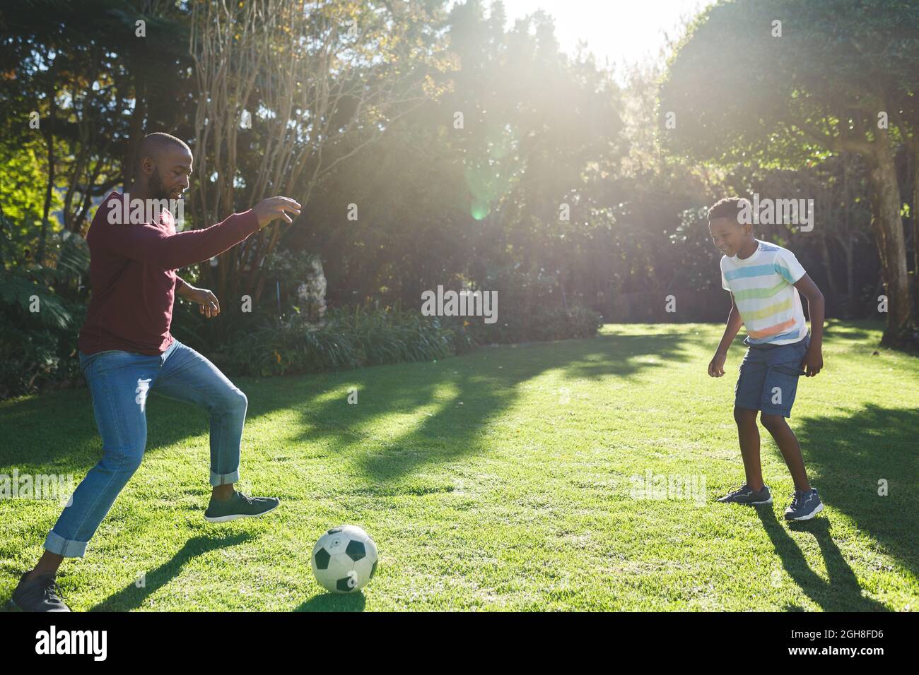 African american father with son having fun and playing football in ...