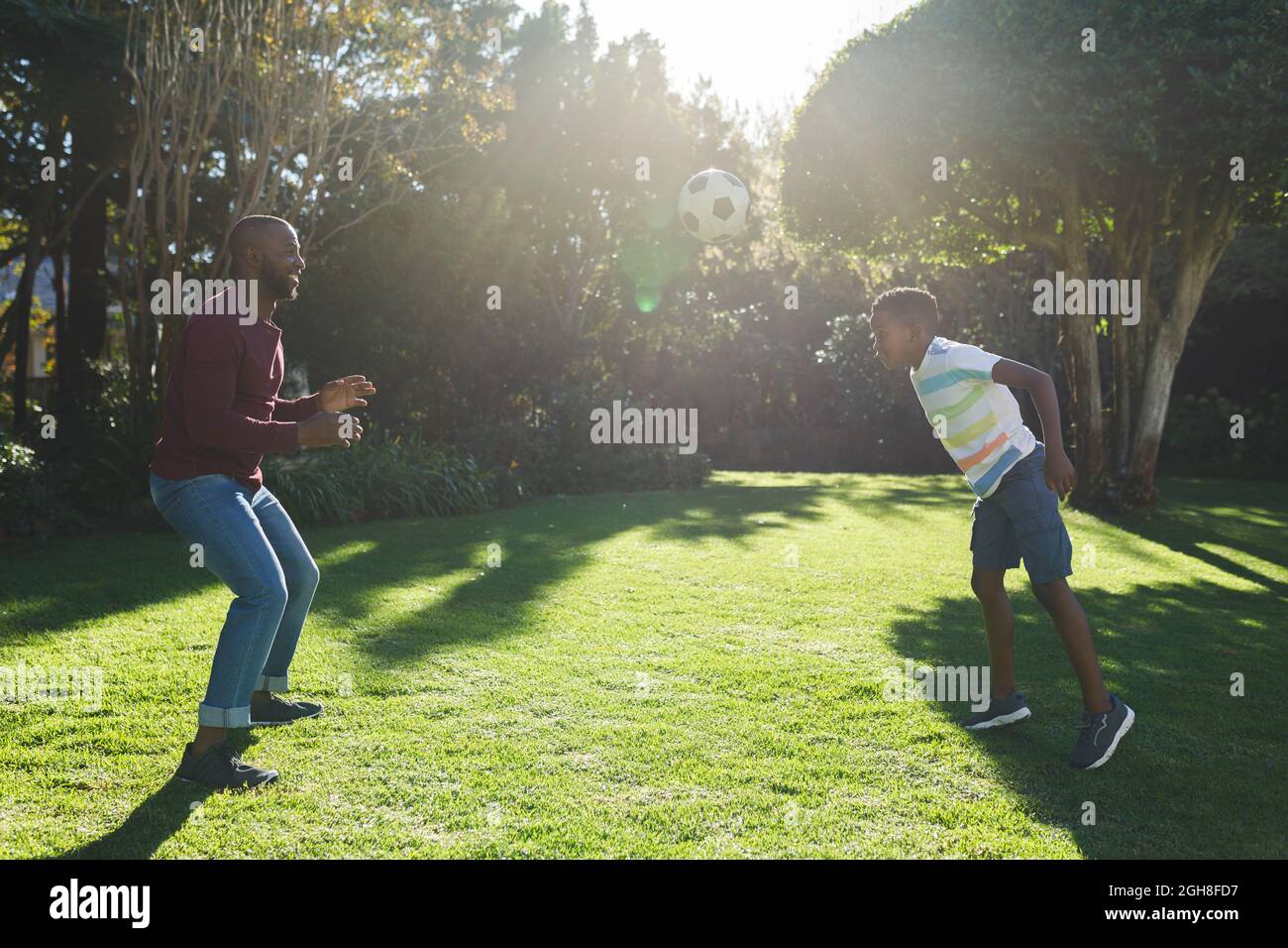 African american father with son having fun and playing football in ...