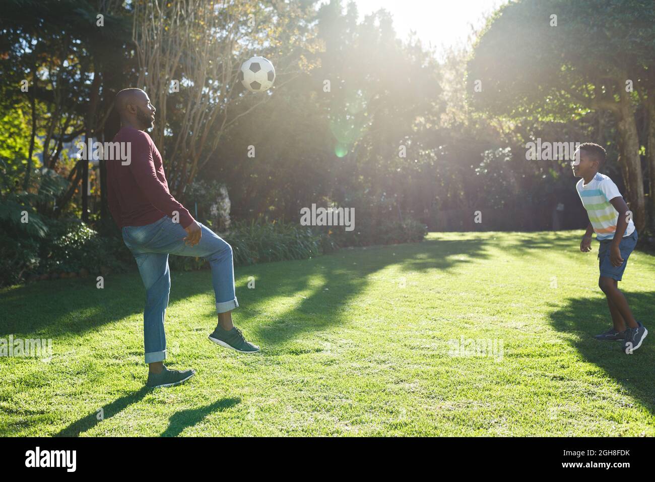 African american father with son having fun and playing football in ...