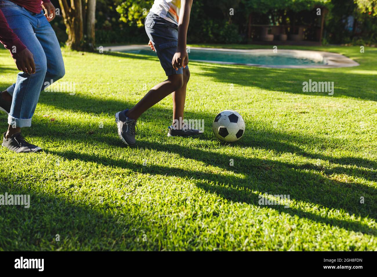 African american father with son having fun and playing football in ...