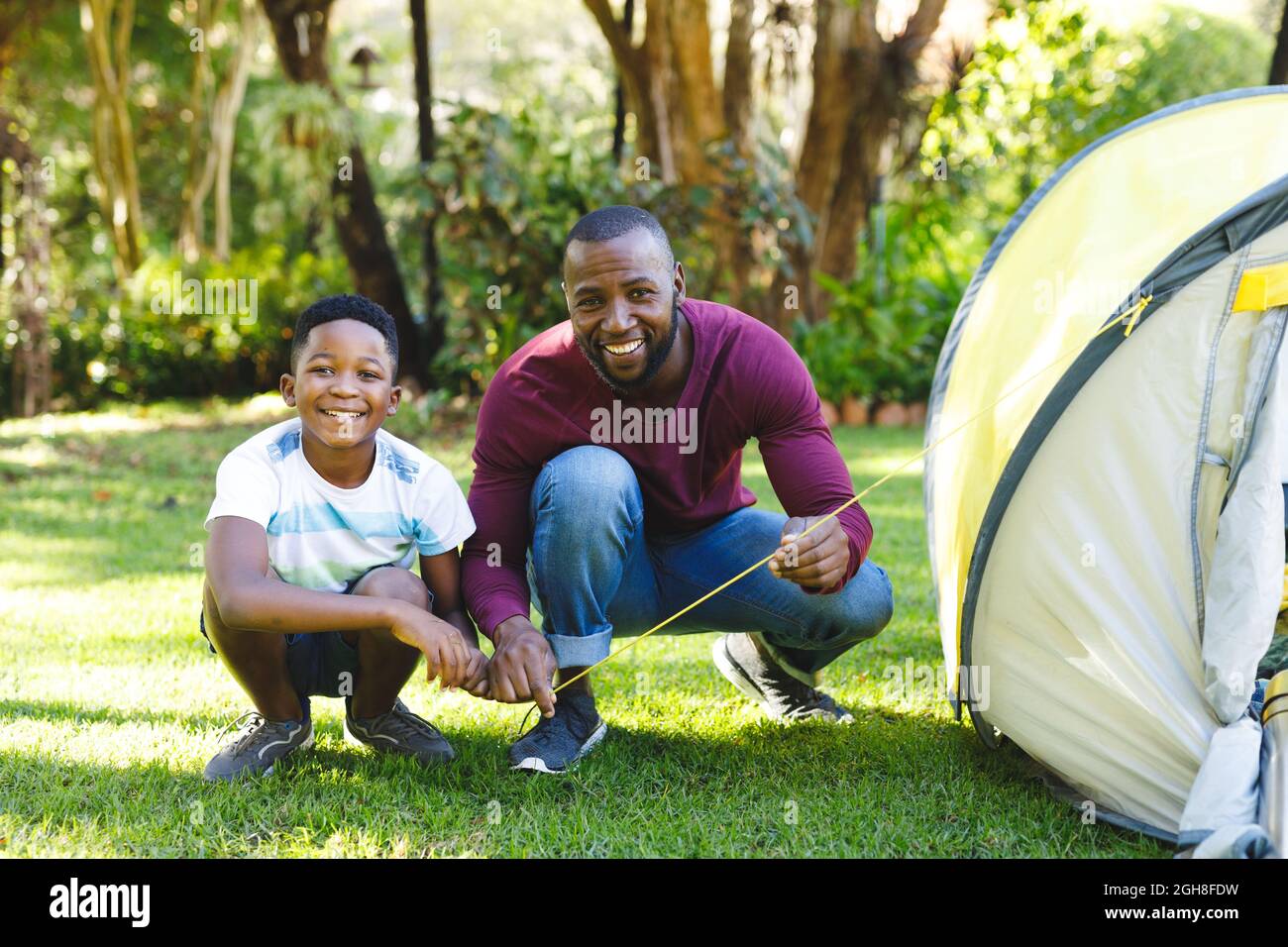Portrait of african american father with son having fun and pitching tent in garden Stock Photo