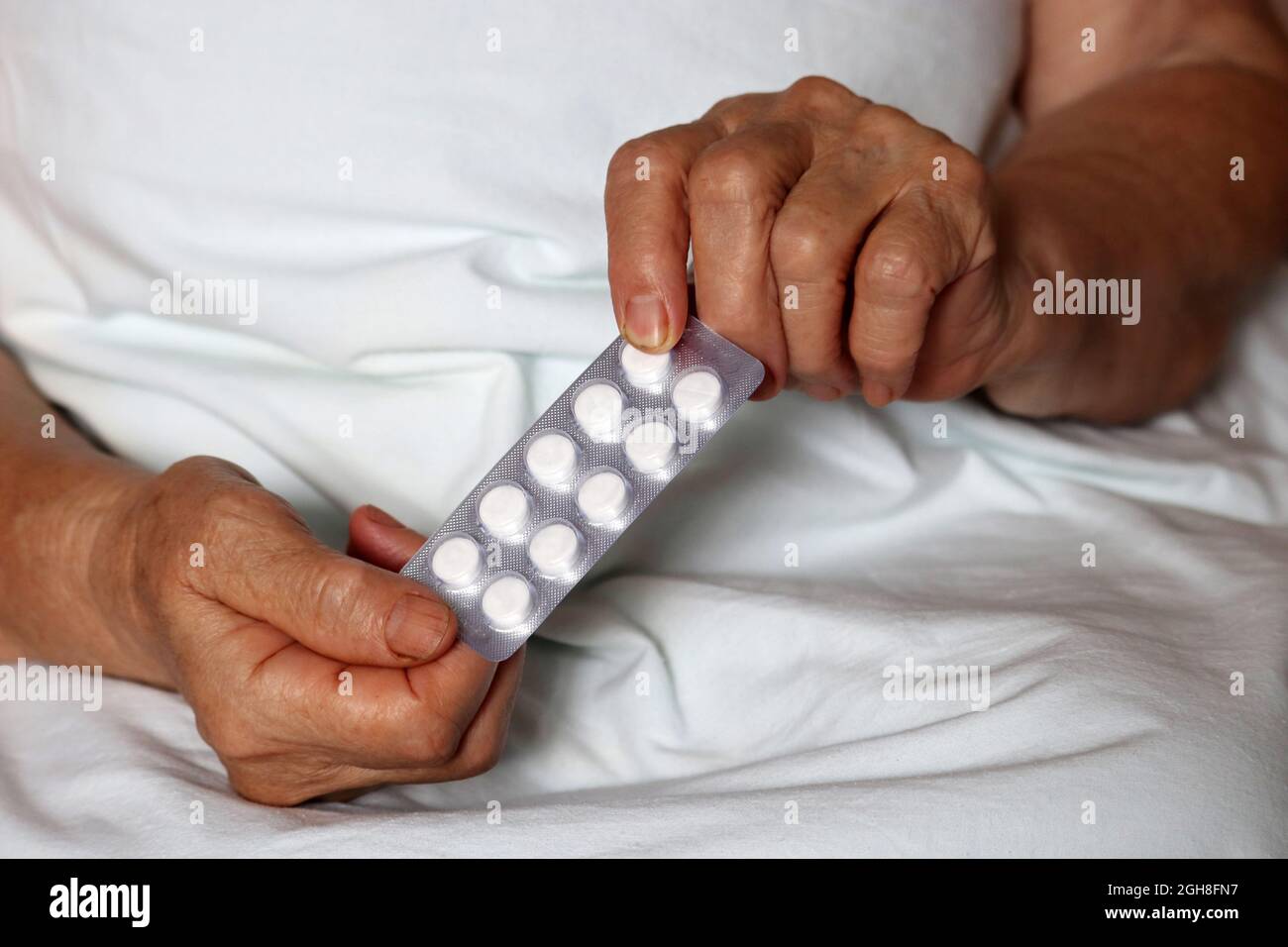 Pills in wrinkled hands of elderly woman. Medication in pack, taking sedatives, antibiotics or vitamins in old age Stock Photo