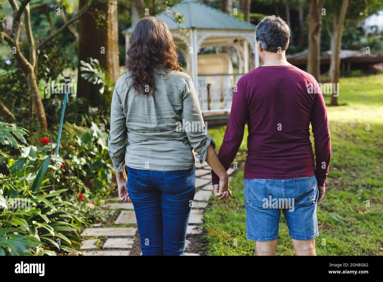 Happy senior caucasian couple holding hands walking in sunny garden ...