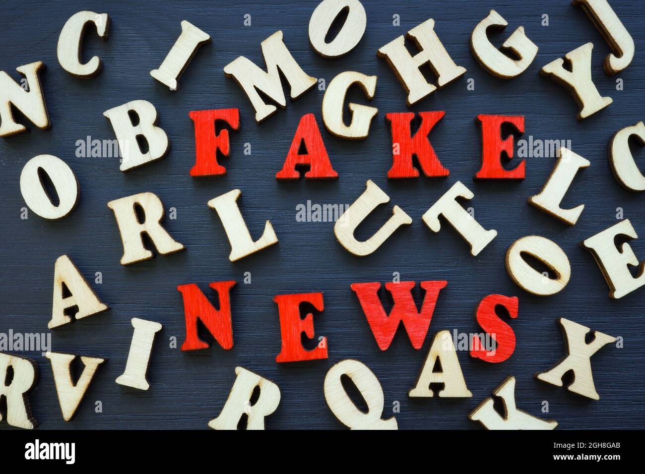 Fake news from red letters and lot of wooden letters. Stock Photo