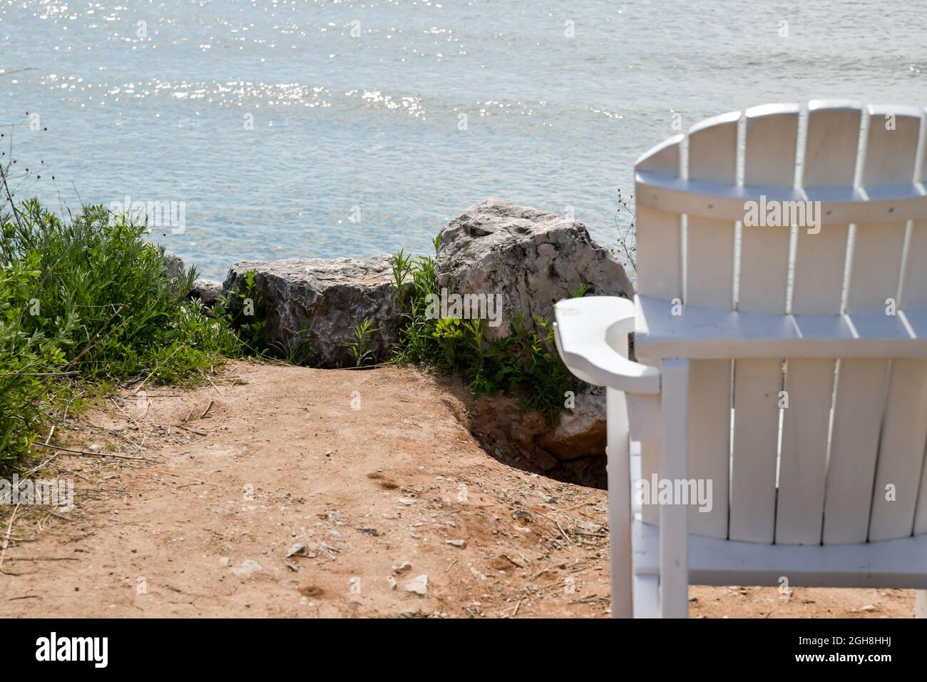 Empty White Adirondack chair along the sand Lake Michigan beach Stock Photo