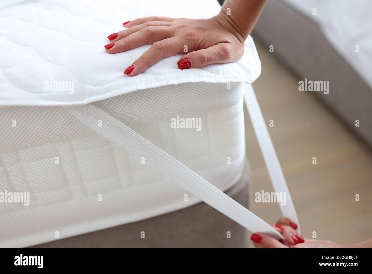Woman puts blanket or mattress topper on bed closeup Stock Photo Alamy