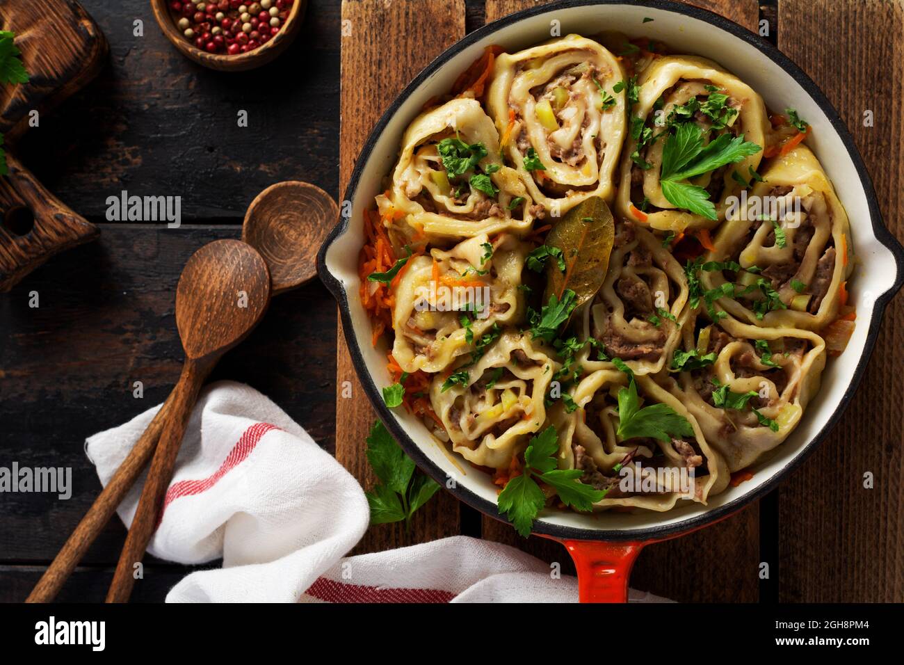 Meat dough rolls with meat or lazy dumplings in a cast-iron pan on an old rustic wooden background. Top view Stock Photo