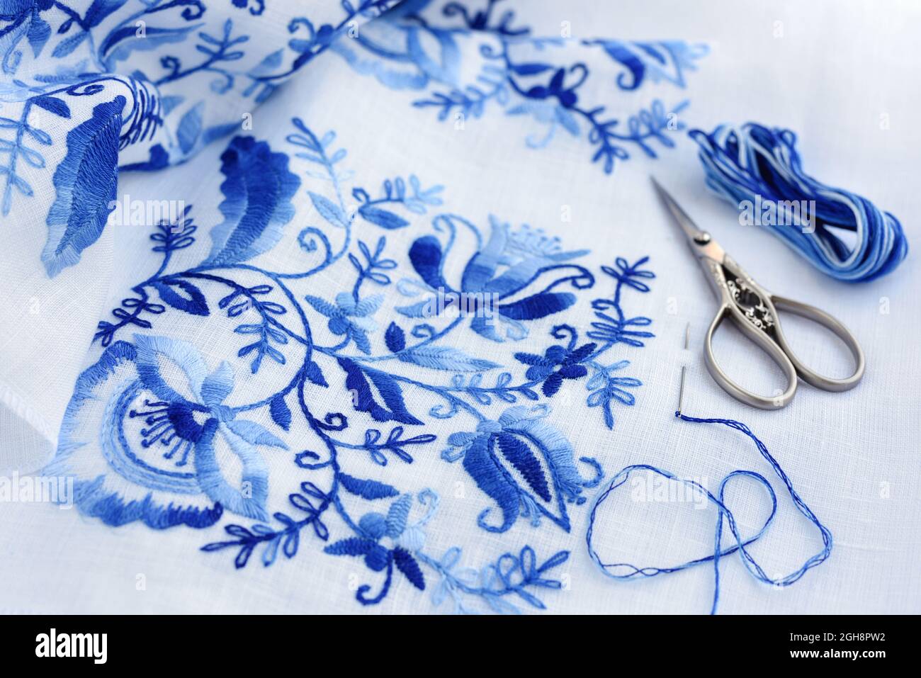 Embroidery, thread and scissors. Blue floral ornament on a white ...
