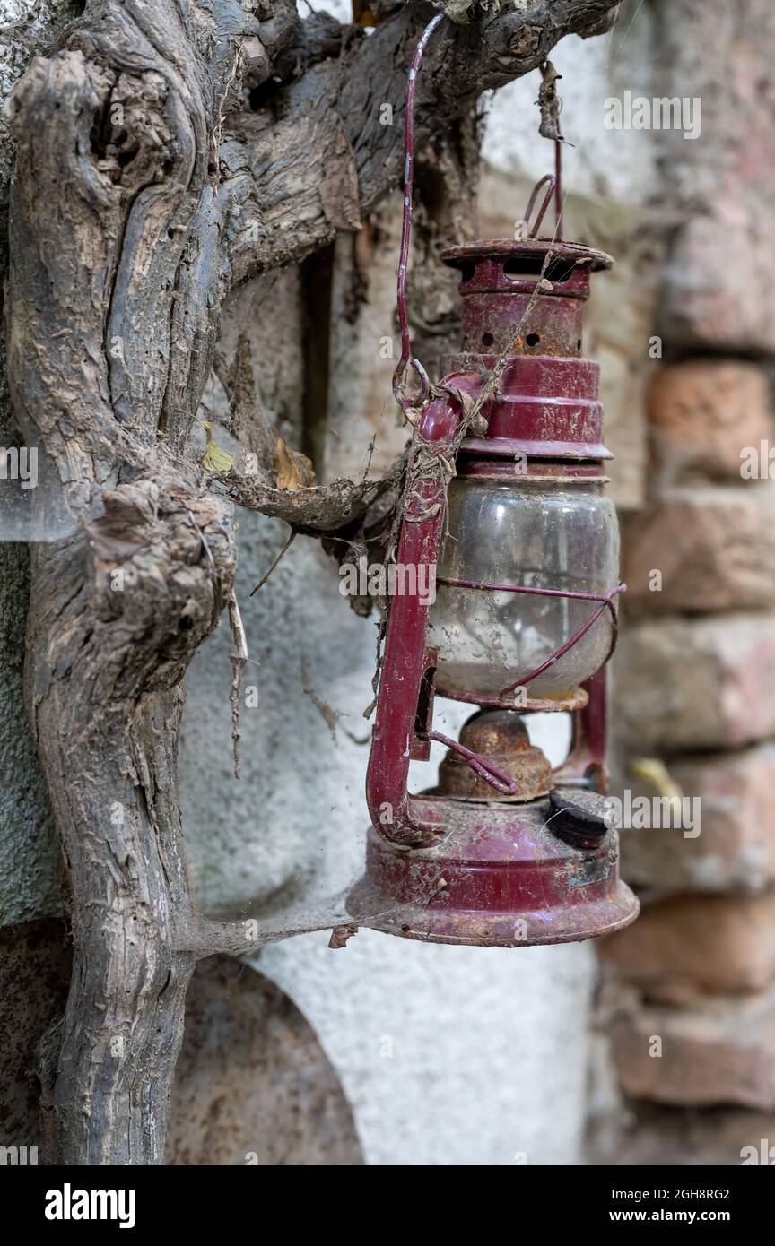 An old rusty oil lamp hangs on a wall, covered with cobwebs and dust
