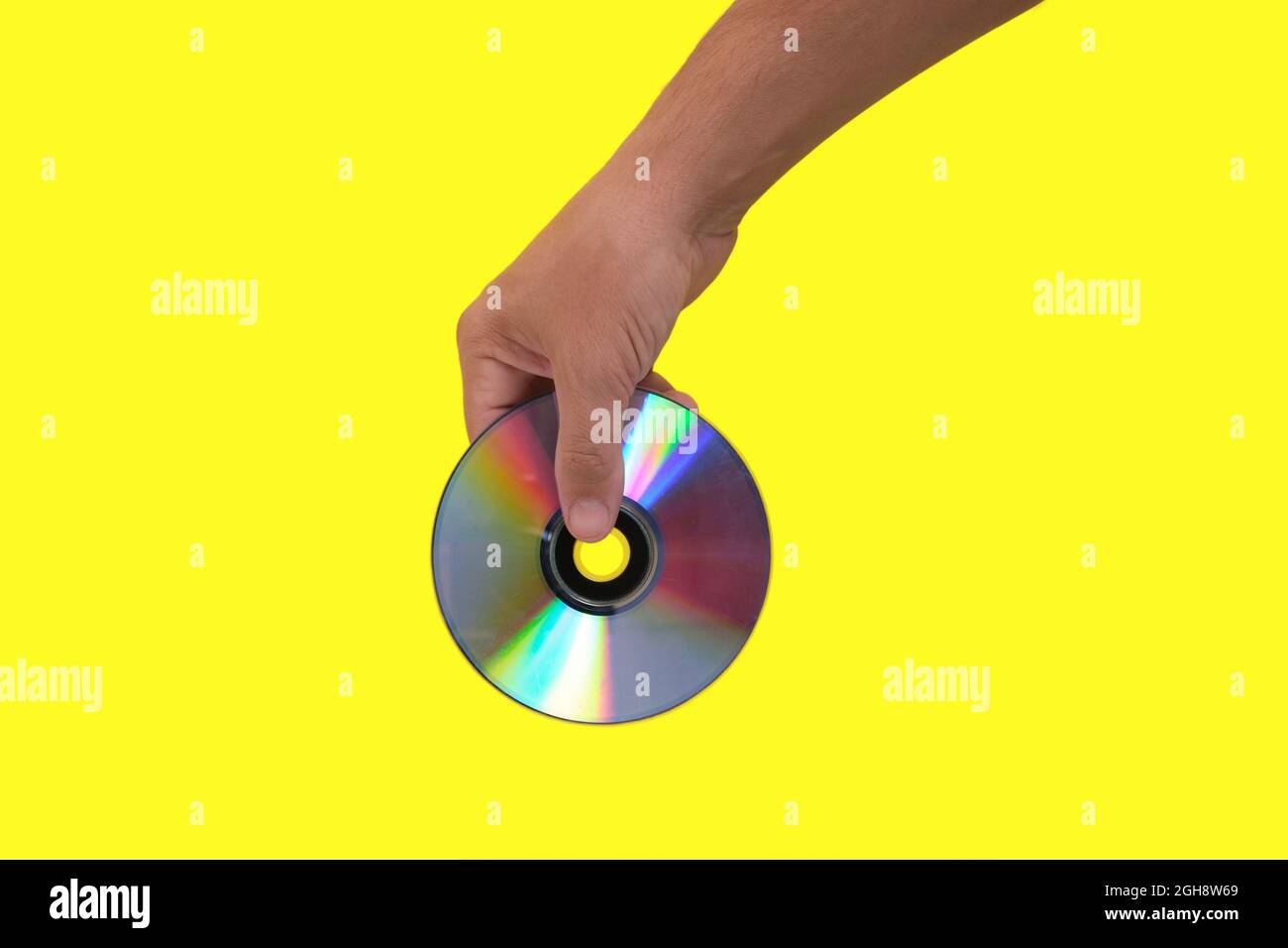 Scratched CD in your hand on a yellow background, outdated technologies Stock Photo