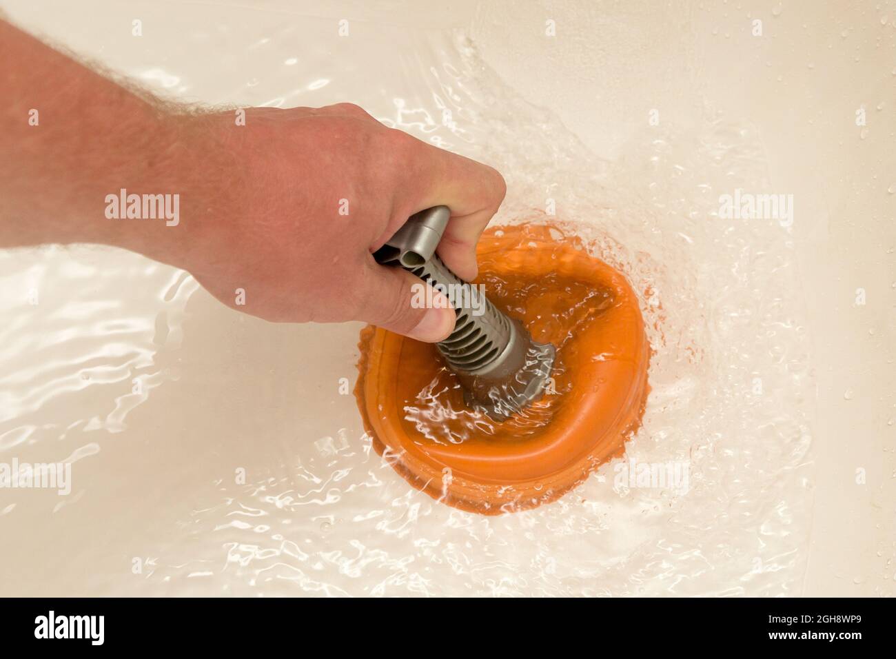 A man's hand with a plunger in the bath. Cleaning pipes from blockages