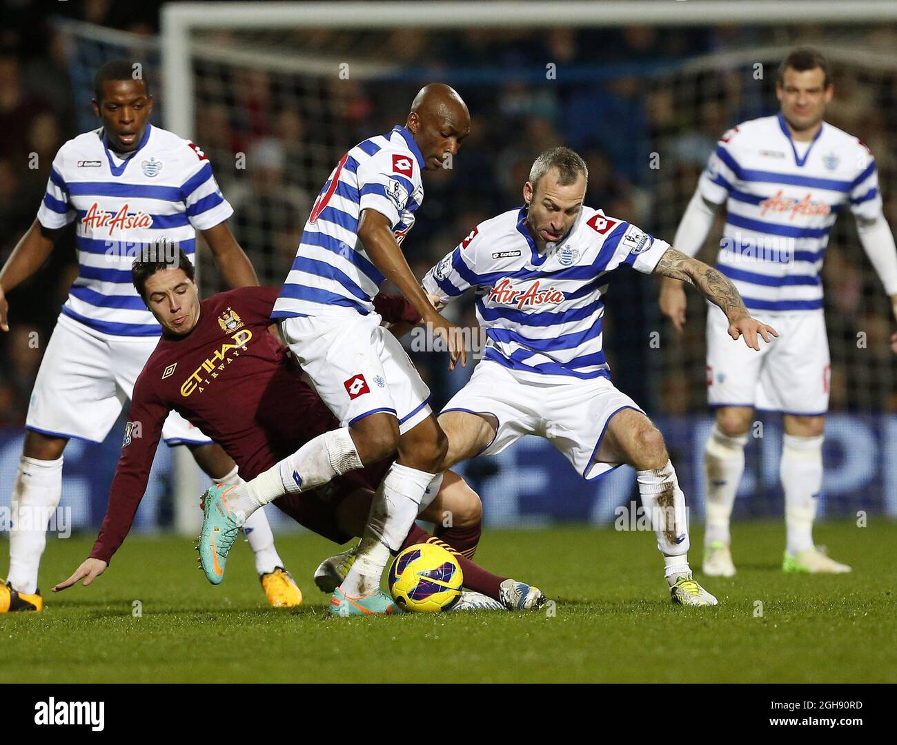 QPR's Stephane Mbia and Shaun Derry tussle with Manchester City's Samir Nasri during the Barclays Premier League between QPR and Manchester City at the Loftus Road in London on January 29, 2013. Stock Photo