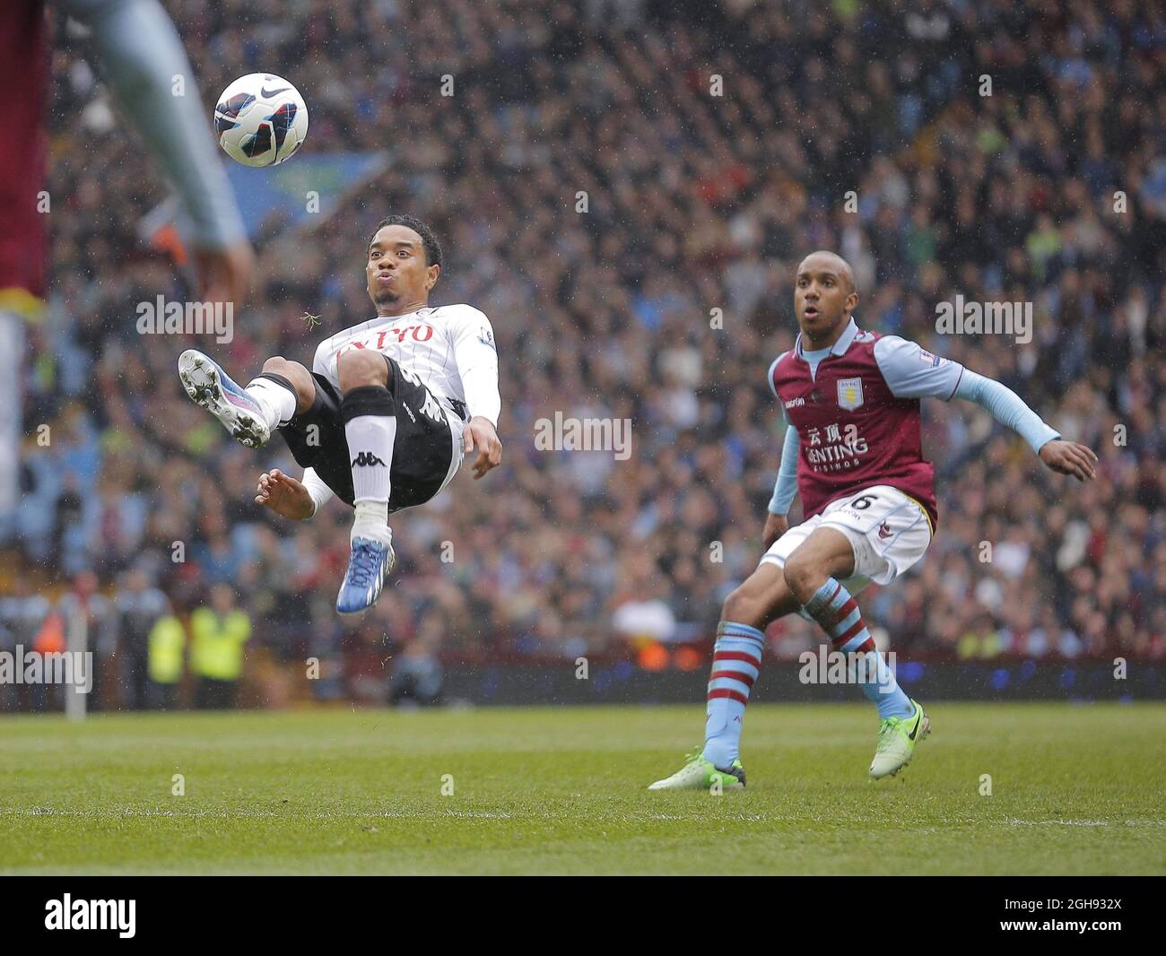 Eyong Enoh of Fulham (left) gets in an overhead kick with Fabian Delph of Aston Villa looking on during the Barclays Premiership match between Aston Villa and Fulham in Villa Park, UK on April 13, 2013. Stock Photo