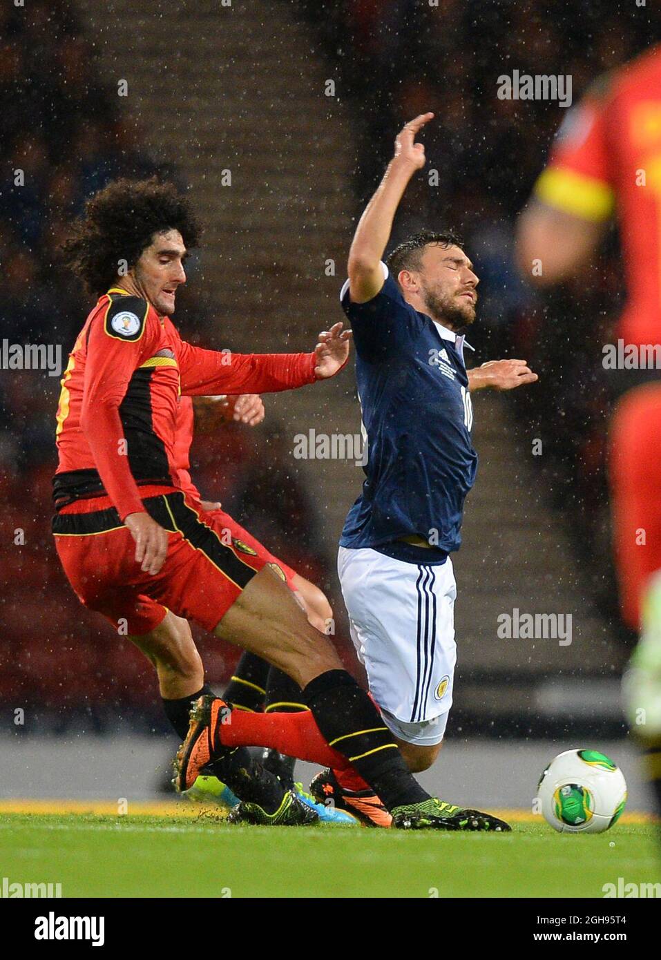 Marouane Fellaini of Belgium tackles Robert Snodgrass of Scotland leading to a yellow card during the 2014 FIFA World Cup Qualifying, Group A match between Scotland and Belgium at the Hampden Park Stadium in Glasgow, Scotland on September 6, 2013. Stock Photo