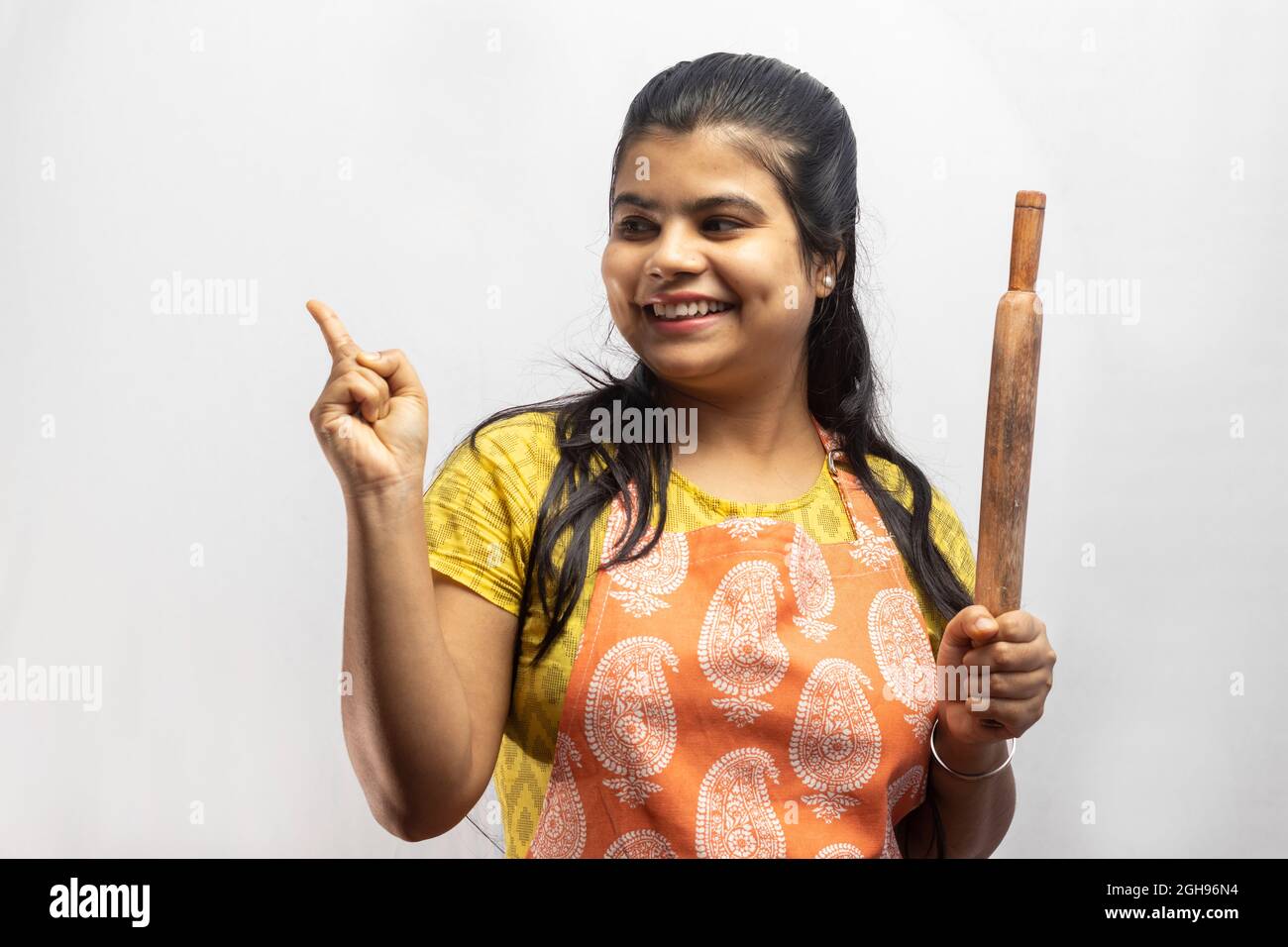 A pretty Indian housewife woman in cooking apron with wooden