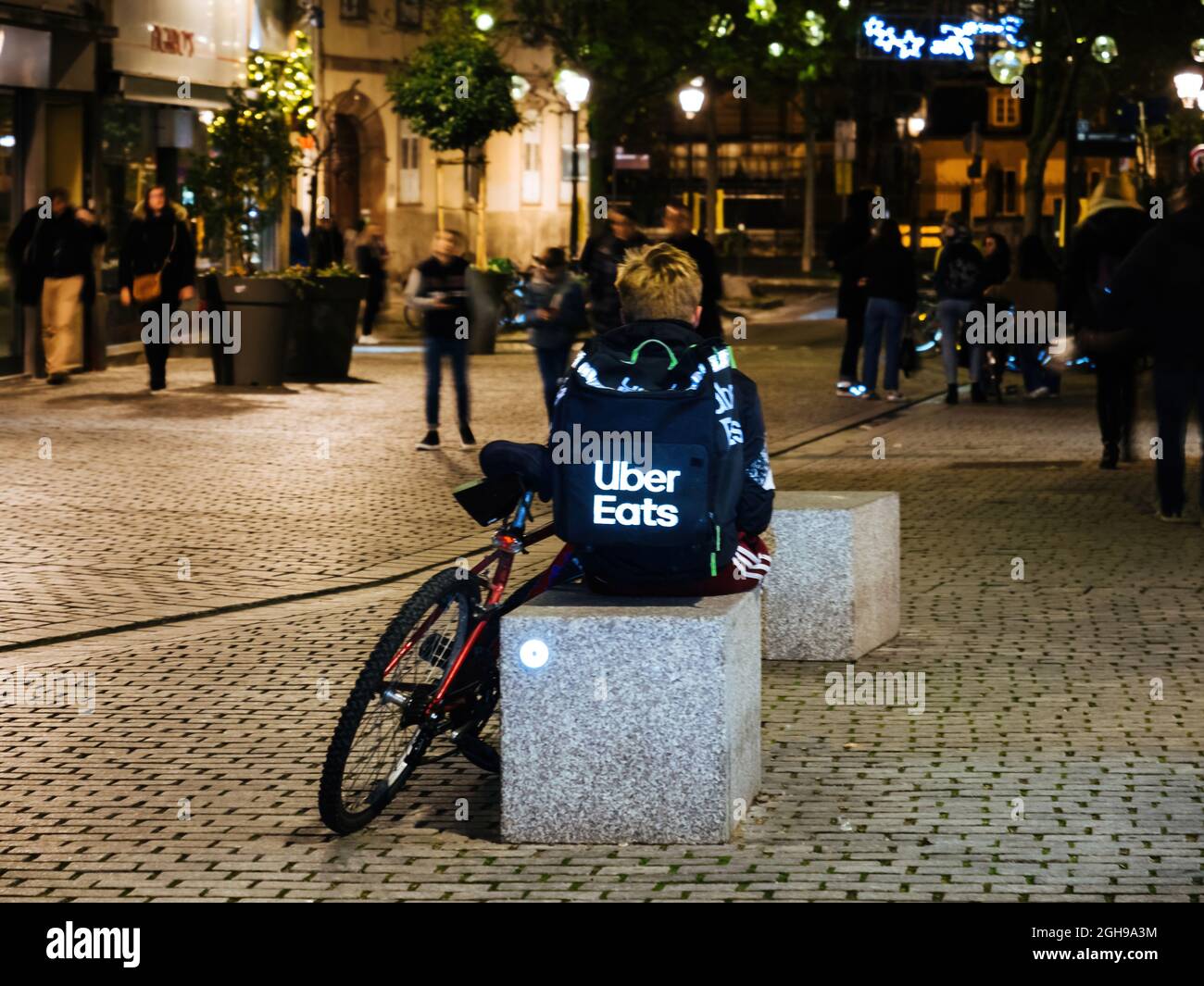 Lonely uber eats app driver delivery young man sitting on the stone
