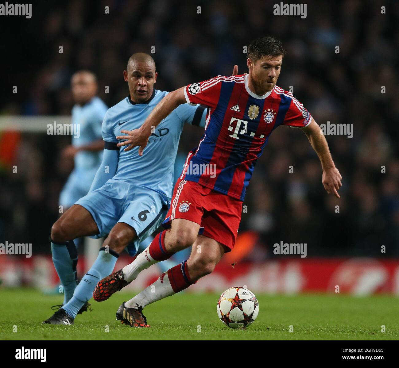 Fernando of Manchester City and Xabi Alonso of Bayern Munich during the Champions League Group E match between Manchester City and Bayern Munich held at Etihad Stadium in England on Nov. 25, 2014. Stock Photo