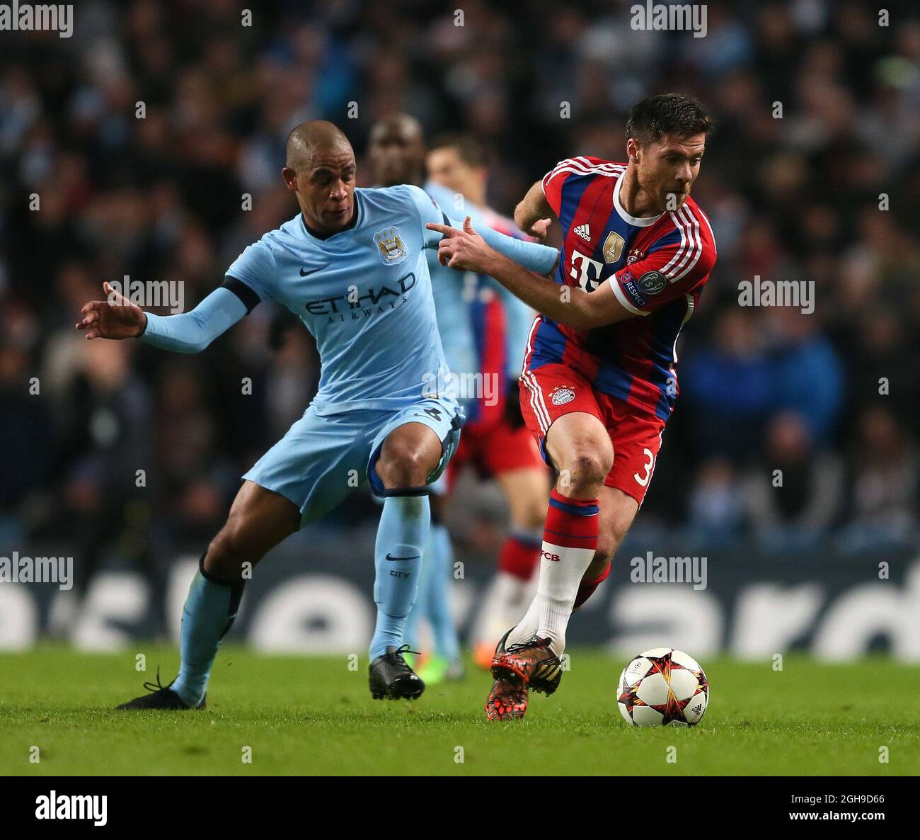 Fernando of Manchester City and Xabi Alonso of Bayern Munich tackles during the Champions League Group E match between Manchester City and Bayern Munich held at Etihad Stadium in England on Nov. 25, 2014. Stock Photo