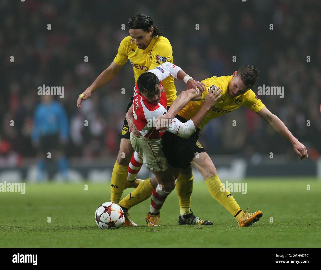 Arsenal's Alexis Sanchez tussles with Dortmund's Neven Subotic and Kevin Grosskreutz during the UEFA Champions League between Arsenal and Borussia Dortmund in Emirates Stadium, England on 26th November 2014. David Klein/ Stock Photo