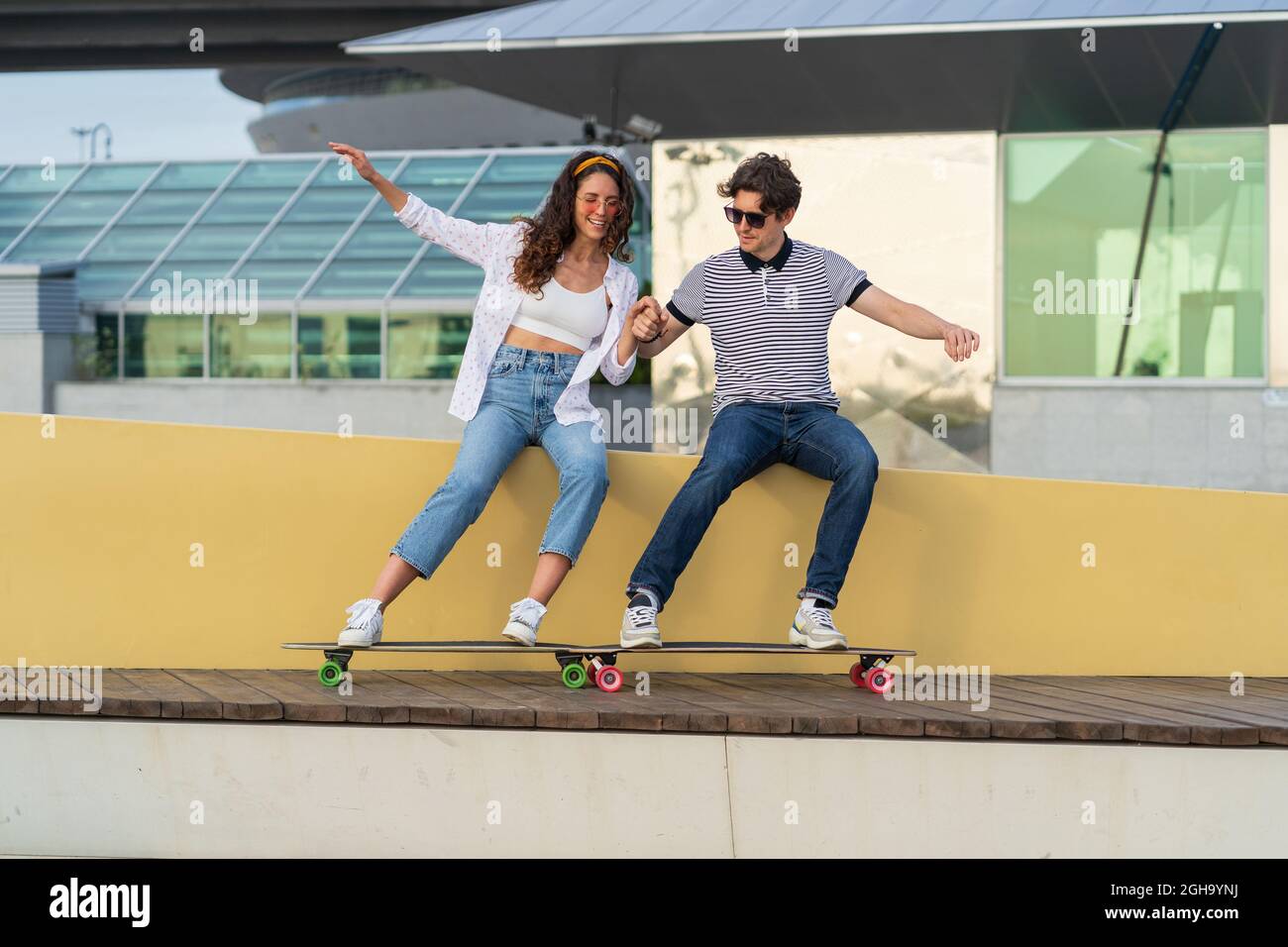 Carefree hipster man and woman young couple having fun after skateboarding laugh enjoy time together Stock Photo
