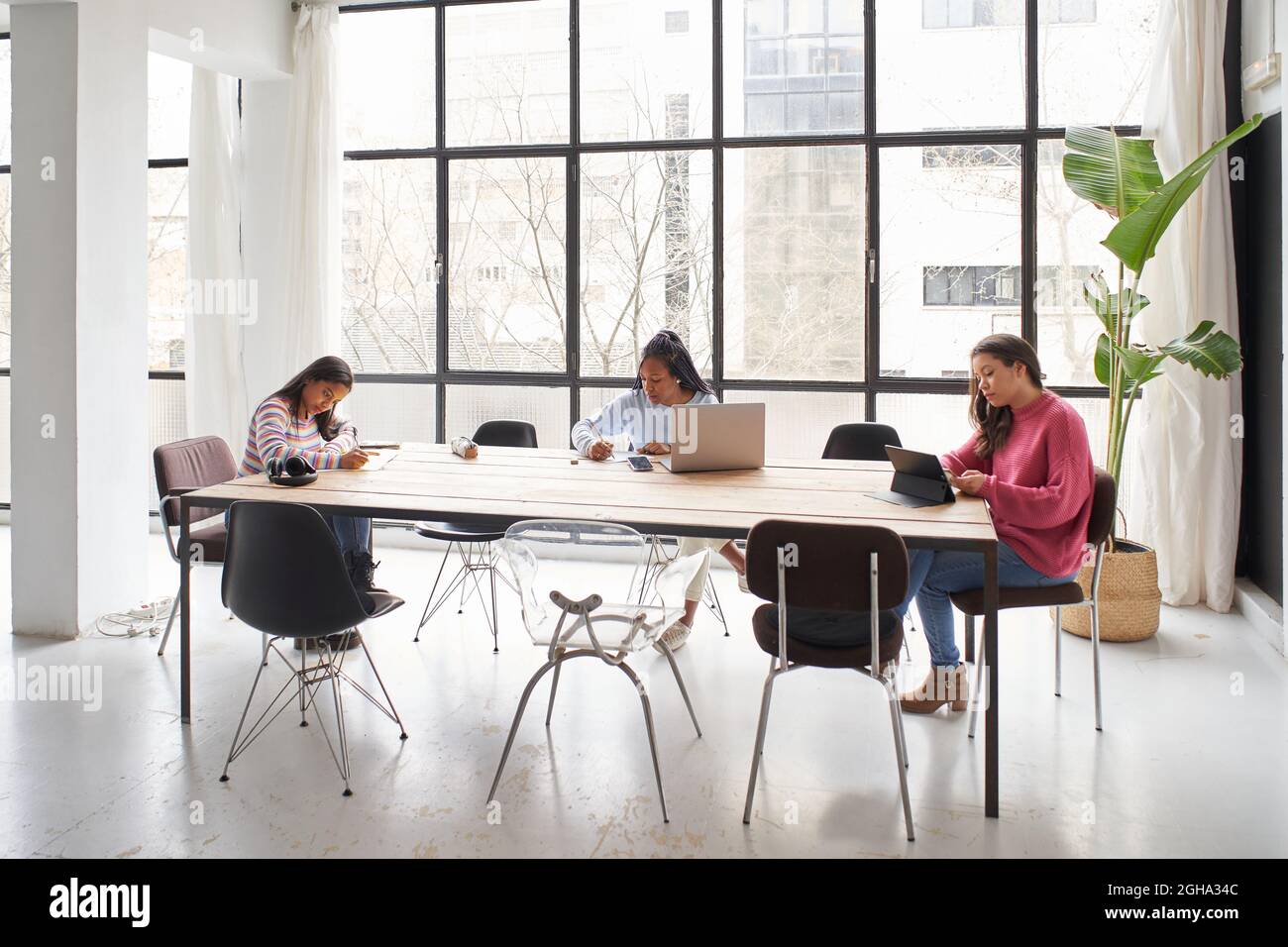 In the office. Three businesswomen work together without masks while keeping a safe distance. Stock Photo