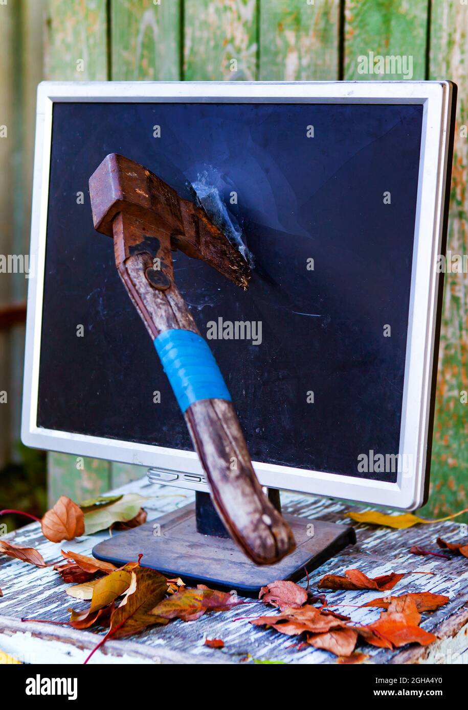 Axe in a Computer Screen Monitor on the Old Planks Background outdoor Stock Photo