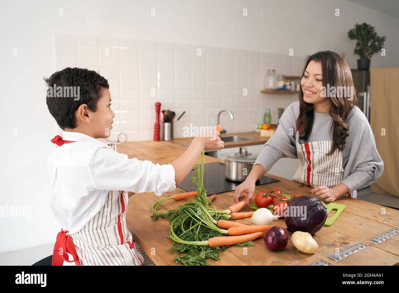 Mother teaching the name of different vegetables to her son in the kitchen. Healthy eating. Stock Photo