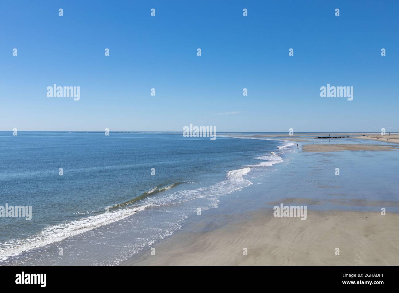 Receding tide on beach at Tybee Island USA, distant walkers