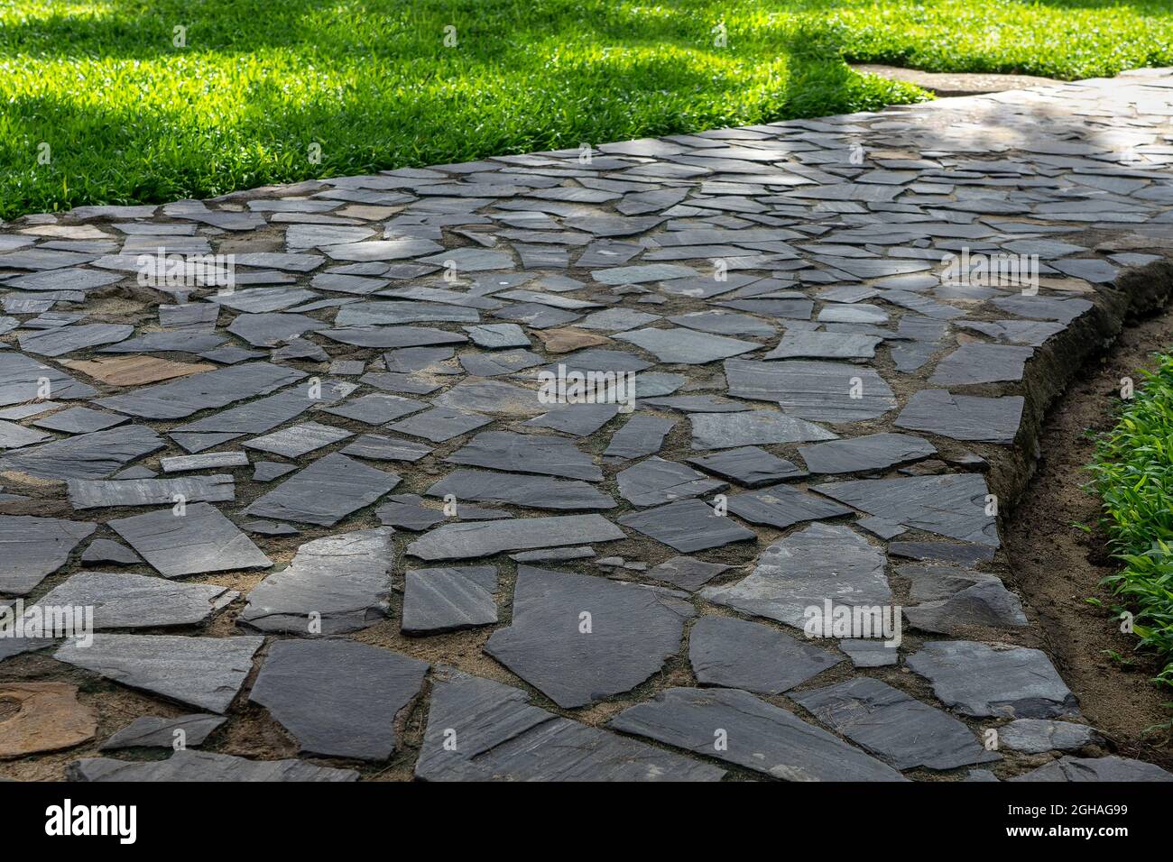 Grey cobblestone at the park walkway.  Garden footpath made of grey paving stone Stock Photo
