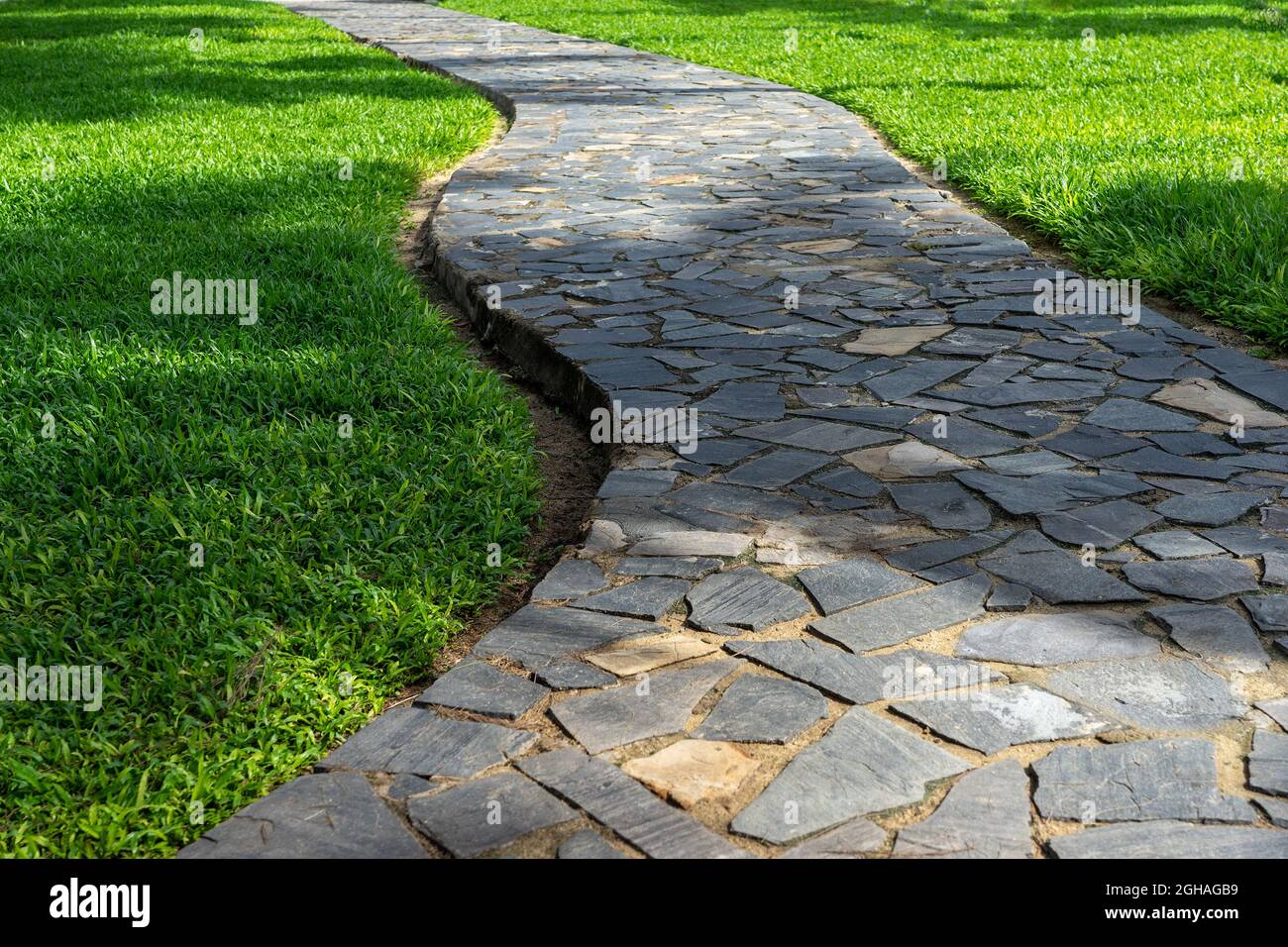 Garden waving stone pathway among green lawn. City park  landscape design. Stock Photo