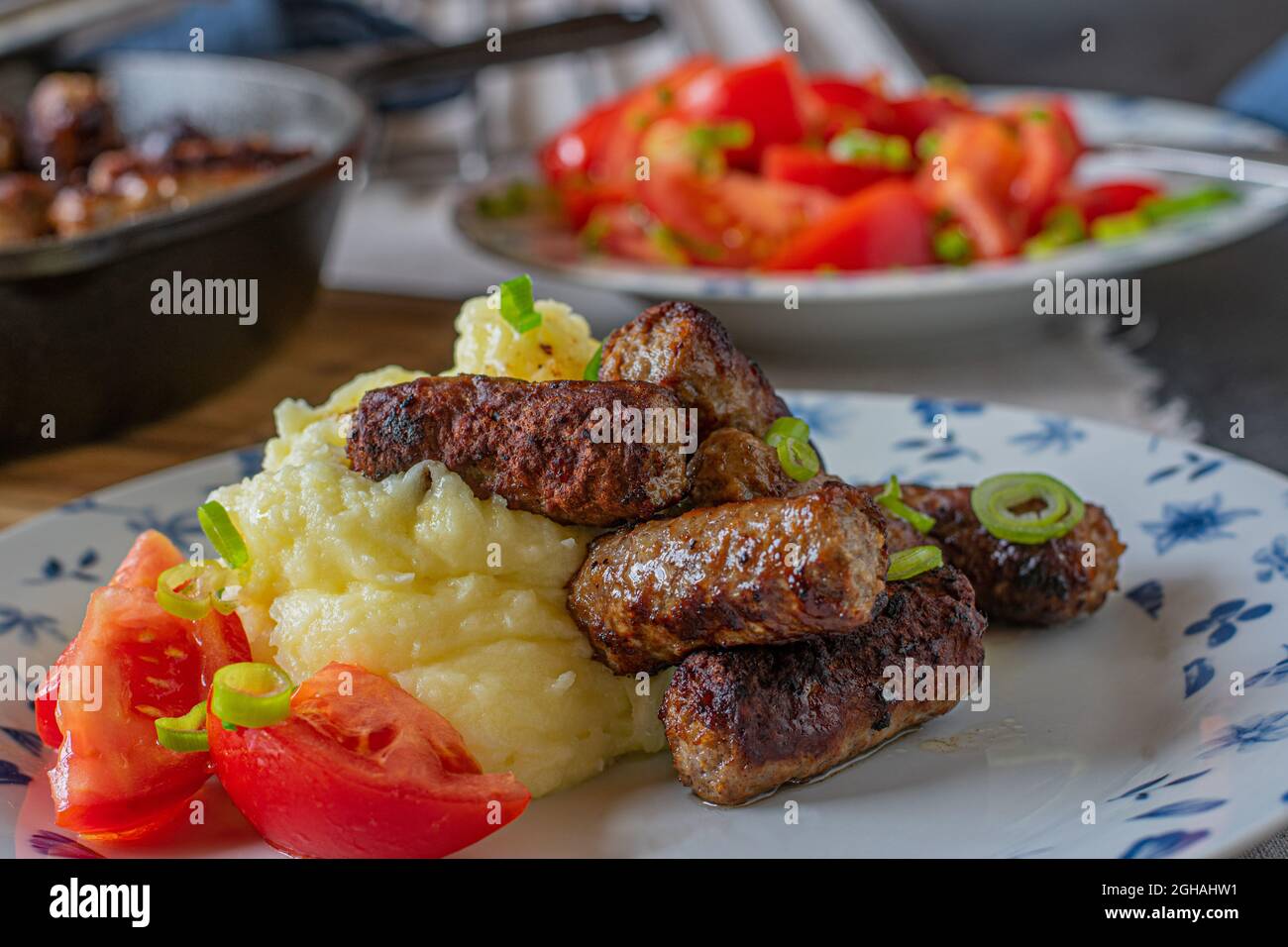 Cevapcici with mashed potatoes and tomato salad Stock Photo